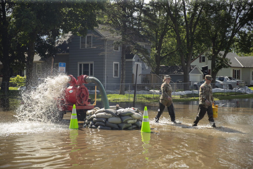 National Guard soldiers walk back by a water pump on a flooded street in Waterville, Minnesota on June 25. Credit: Christopher Mark Juhn/Anadolu via Getty Images